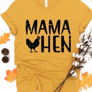 May include: A mustard yellow t-shirt with black text that reads "Mama Hen" and a black silhouette of a chicken.