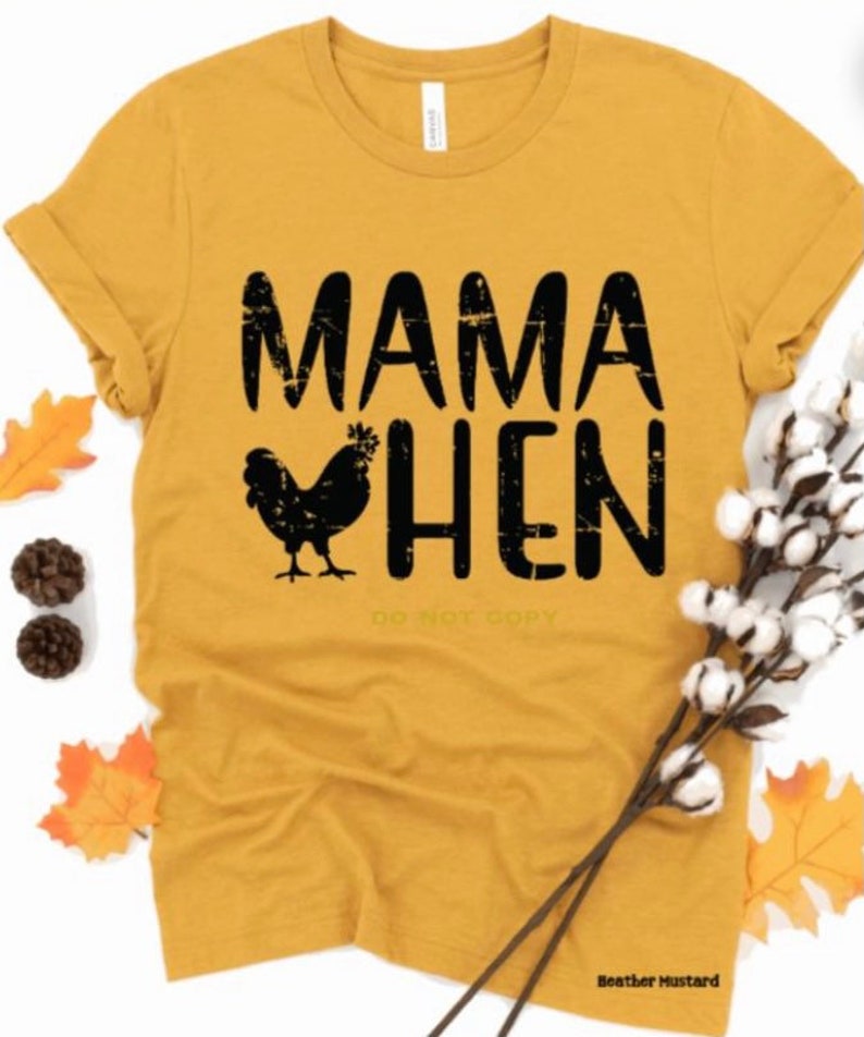 May include: A mustard yellow t-shirt with black text that reads "Mama Hen" and a black silhouette of a chicken.