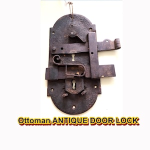 May include: Antique Ottoman door lock made of metal with a keyhole and a latch. The lock is rusty and has a dark brown color.