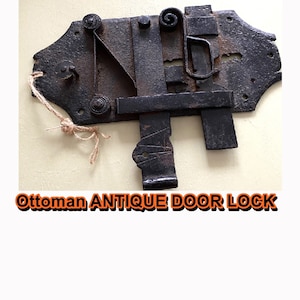 May include: Antique Ottoman door lock made of metal with intricate details. The lock is in a worn condition, showing signs of age and use. It features a keyhole, a latch, and a lever.