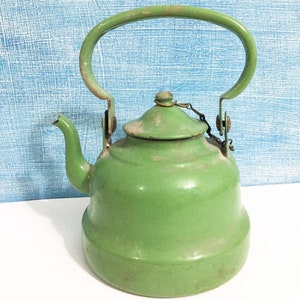 May include: A vintage green enamel teapot with a metal handle and lid. The teapot has a worn, rustic look.