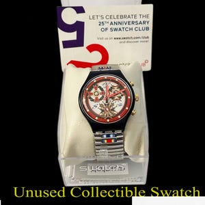 May include: Unused collectible Swatch watch with a black plastic case and a silver metal band. The watch face has a white background with red and gold accents. The watch is in a clear plastic display case with a white background and the word "swatch" printed in black.