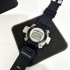 May include: A black and silver Casio watch with a black rubber band. The watch face has a digital display with the text "SENSOR ADJUST CASIO DEPTH METER TH 3-22 18:5 156 WATER 500M LIGHT ART STOR" and the words "MARINE GEAR" are printed on the band.