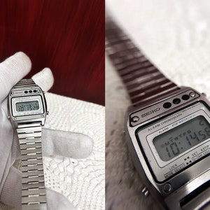 Puede incluir: Un reloj digital Seiko plateado con una esfera negra y una correa de metal plateado. El reloj tiene una pantalla digital que muestra la hora, la fecha y el d&iacute;a de la semana. El reloj tambi&eacute;n tiene una funci&oacute;n de cron&oacute;grafo.