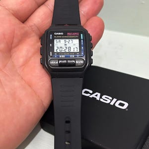 May include: A black Casio Wrist Remote Controller alarm chronograph digital watch with a black resin strap. The watch face displays the text CASIO, WRIST REMOTE CONTROLLER, ALARM CHRONOGRAPH, and shows the time 20:28 and date SA 9-27 on the screen.