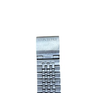 May include: A silver-toned Casio watch band with a rectangular link design. The band features the brand name "CASIO" on the clasp. The band is made of metal and has a polished finish.