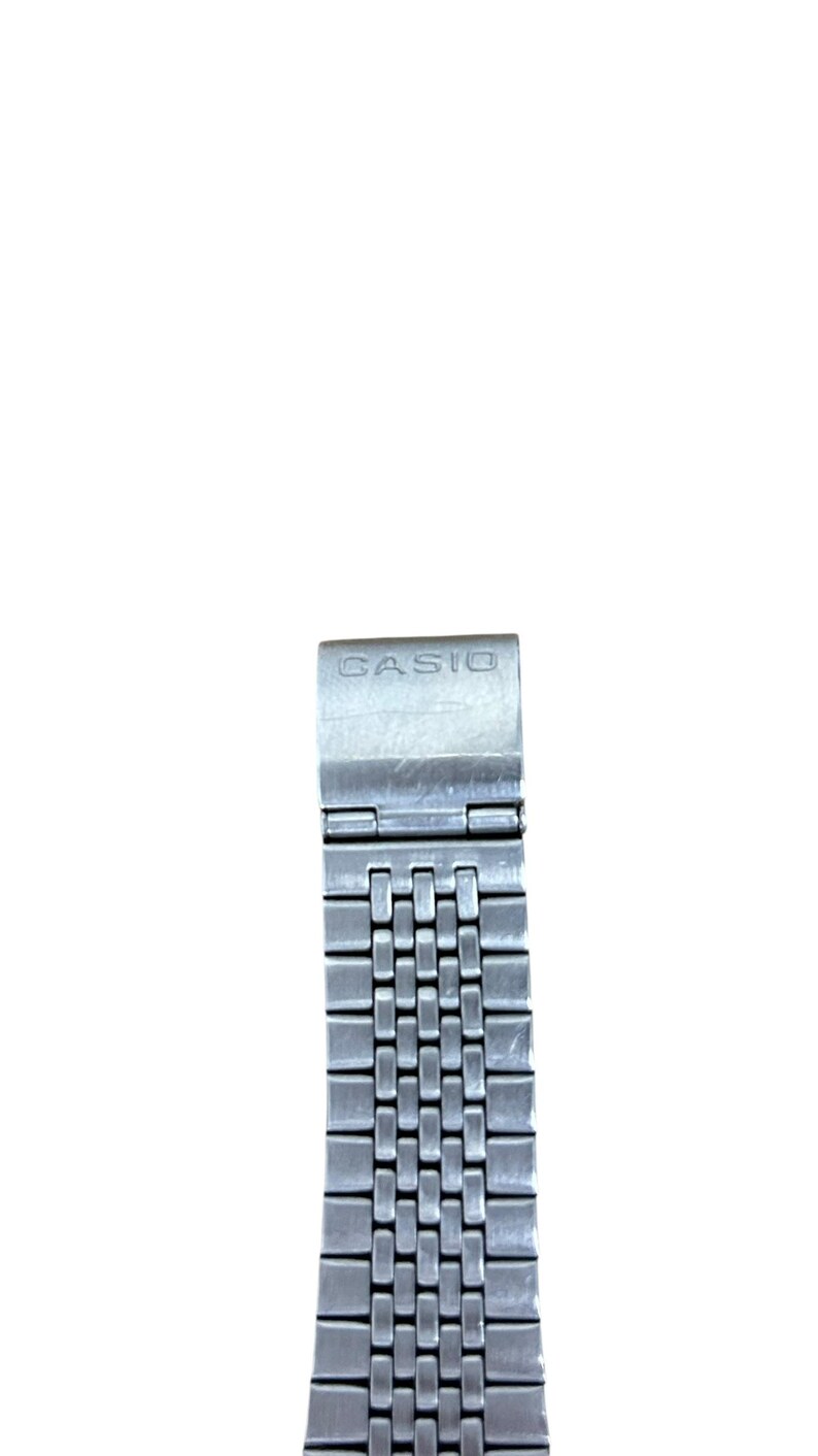 May include: A silver-toned Casio watch band with a rectangular link design. The band features the brand name "CASIO" on the clasp. The band is made of metal and has a polished finish.