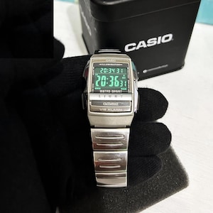 Può includere: Un orologio da polso Casio argentato con un display digitale nero che mostra l'ora 20:36:31. L'orologio ha un cinturino nero e un quadrante argentato con le parole "Casio", "Illuminator", "Water Resist", "Light", "Futurist" e "Vib Alarm" stampate su di esso.