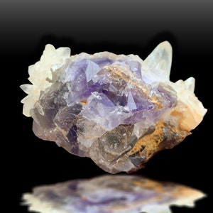 May include: A cluster of purple fluorite crystals with clear quartz crystals, showing a variety of shapes and sizes. The fluorite has a deep purple color with some areas of lighter purple and white. The quartz crystals are clear and translucent.