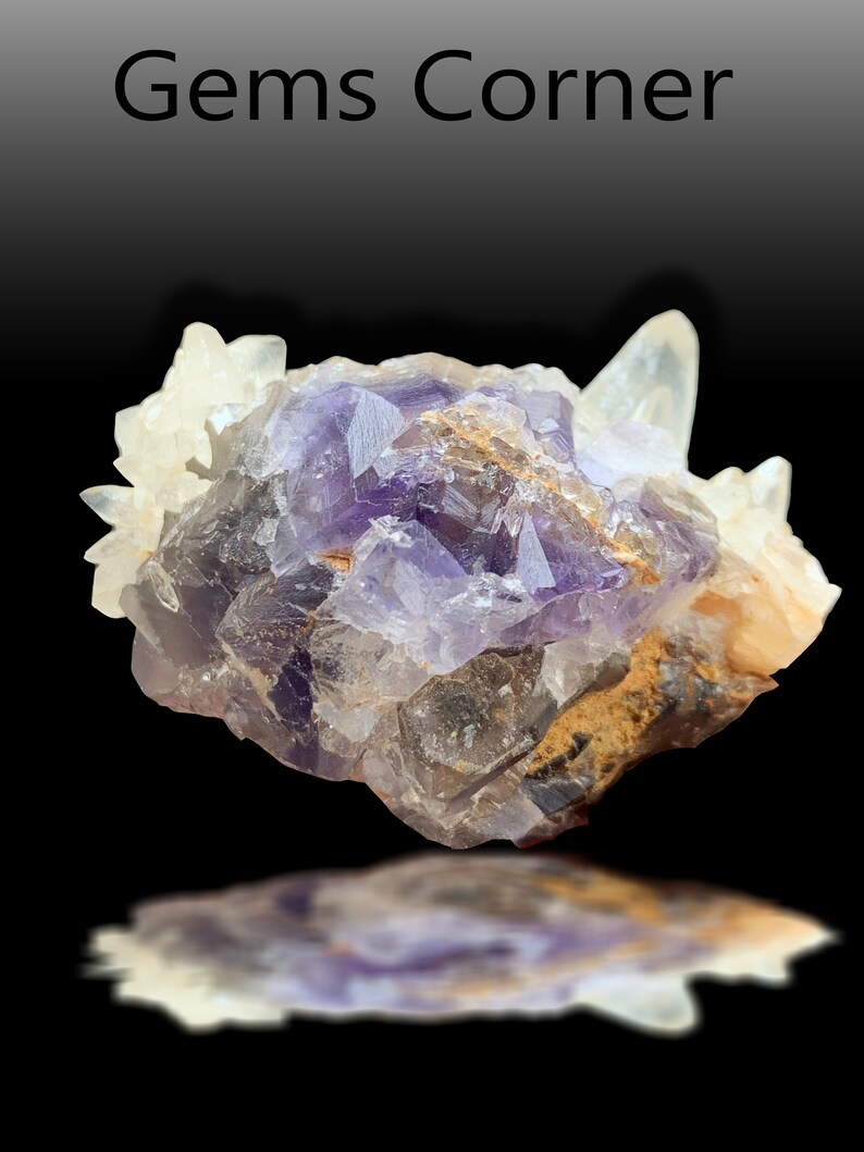 May include: A cluster of purple fluorite crystals with clear quartz crystals, showing a variety of shapes and sizes. The fluorite has a deep purple color with some areas of lighter purple and white. The quartz crystals are clear and translucent.