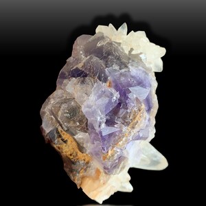 May include: A cluster of purple fluorite crystals with clear quartz crystals. The fluorite crystals have a deep purple color and are translucent. The quartz crystals are clear and have a glassy luster.