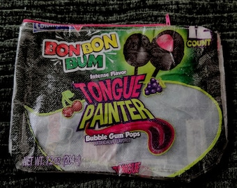 May include: A clear plastic pouch with a pink zipper, featuring the text "BONBON BUM" and "TONGUE PAINTER" in vibrant colors. The pouch contains bubble gum pops and has a net weight of 7.2 oz (204 g).