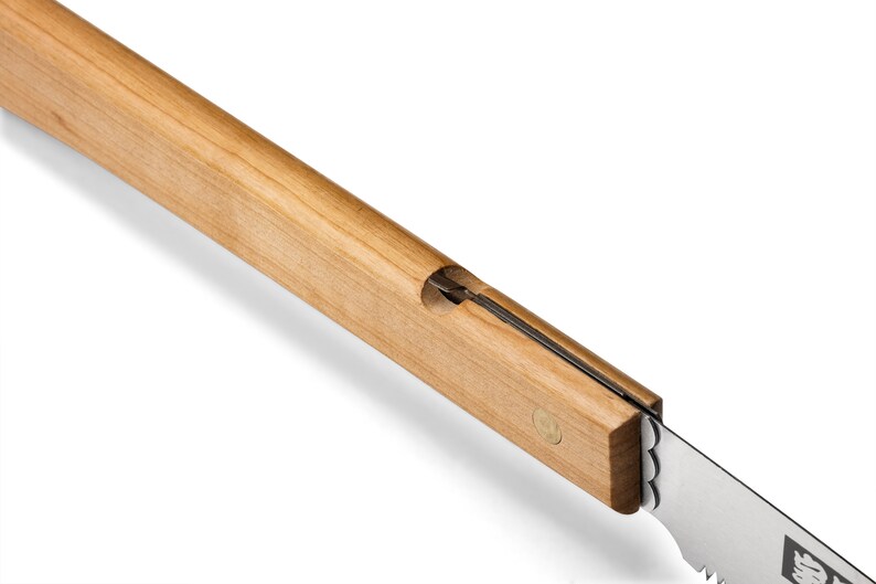 May include: A close-up of a wooden-handled saw with a metal blade. The handle is made of light-colored wood and has a small brass pin near the blade.