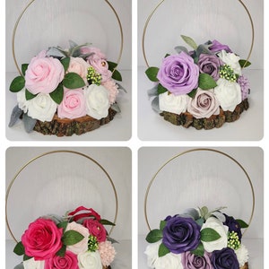 May include: Four floral arrangements on wood slices with gold hoops. The arrangements feature pink, purple, and red roses with white and lavender accents.