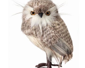 Op de afbeelding: Decoratieve uilfiguur met een realistisch uiterlijk. De uil heeft bruine en witte veren, oranje ogen en een zwarte snavel. Het beeldje staat op bruine poten en heeft veerachtige details.