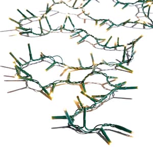 May include: Strands of small, warm white LED lights on green wire, arranged on a white surface. The lights are evenly spaced and appear to be turned on, casting soft shadows. Ideal for holiday or event decorations.