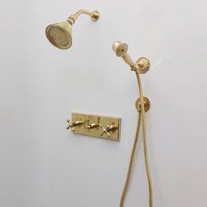 May include: Gold shower head with a handheld shower head and a three-handle shower valve.