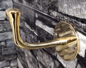 May include: A gold-toned metal hook with a rounded top and a curved arm. The hook is mounted on a round base with a screw.