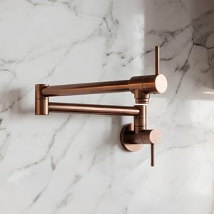 May include: A wall-mounted pot filler faucet with a metallic copper finish. The fixture features a double-jointed, articulating swing arm design with two vertical lever handles, one located at the base and one at the end of the spout assembly.