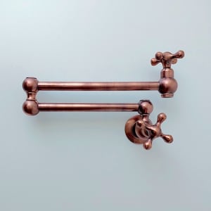May include: A copper-colored double-jointed kitchen faucet with a swivel spout and a cross-shaped handle.
