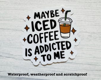 May include: A white die-cut sticker featuring the black text MAYBE ICED COFFEE IS ADDICTED TO ME. The design includes a graphic of a clear plastic cup filled with brown iced coffee, a green straw, and several small brown four-pointed star accents.