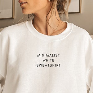 May include: White crew neck sweatshirt with the text "MINIMALIST WHITE SWEATSHIRT" printed on the front.