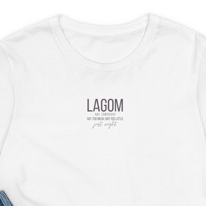 May include: White t-shirt with a black text graphic that reads "LAGOM - Just enough, not too much, not too little, just right."