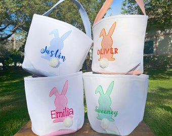 May include: Four white Easter baskets with bunny silhouettes and personalized names. The baskets are lined with pink, blue, green, and orange gingham fabric. The bunnies have fluffy white tails.