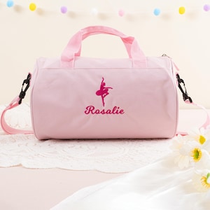 Pu&ograve; includere: Borsa da viaggio in tela rosa con una silhouette di ballerina rosa e il nome "Rosalie" ricamato sul davanti.