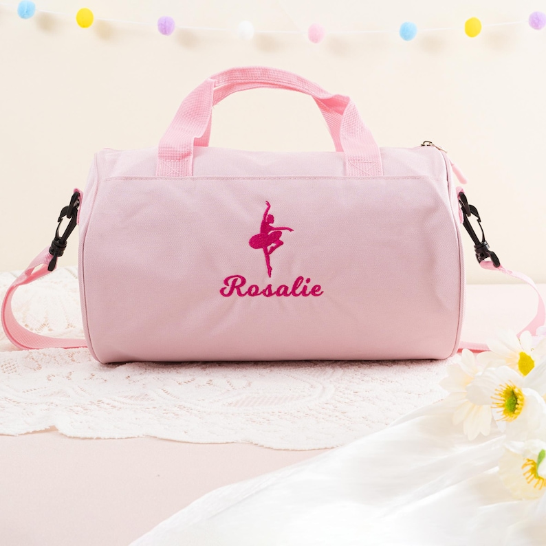 Pu&ograve; includere: Borsa da viaggio in tela rosa con una silhouette di ballerina rosa e il nome "Rosalie" ricamato sul davanti.