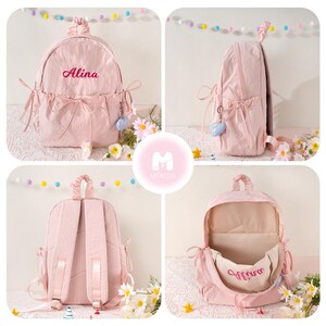 May include: Pink backpack with the name "Alina" embroidered in a cursive font. The backpack has a drawstring closure, side pockets, and decorative bows. A small heart-shaped charm hangs from the side. The interior is visible in one image.