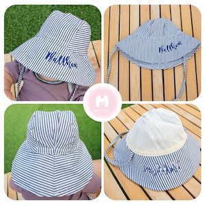 May include: A blue and white striped sun hat with a blue embroidered name "Matthew". The hat has a wide brim and a chin strap.