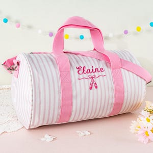 May include: Pink and white striped duffel bag with pink handles and a pink embroidered name "Elaine" with a pair of pink ballet shoes underneath.