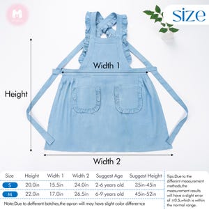 May include: A light blue denim apron with ruffled trim and two pockets. The apron has adjustable straps that cross at the back. The apron is available in two sizes: S (20 inches tall, 15.5 inches wide) and M (22 inches tall, 17 inches wide).