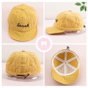 May include: A yellow baseball cap with the name "Sarah" embroidered on the front. The cap has a black adjustable strap and a white inner lining.