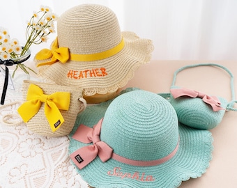 May include: A collection of straw hats and matching purses. One hat is beige with a yellow band and bow, the name "HEATHER" embroidered in orange. Another is light blue with a pink band and bow, the name "Sophia" embroidered in pink.
