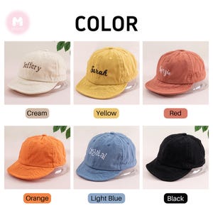 May include: Six different colored baseball caps with embroidered names on the front. The colors are cream, yellow, red, orange, light blue, and black.