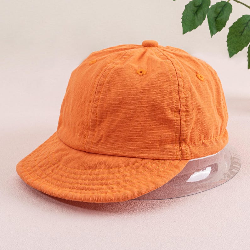 May include: A bright orange baseball cap with a curved brim. The cap is made of a soft, textured fabric.