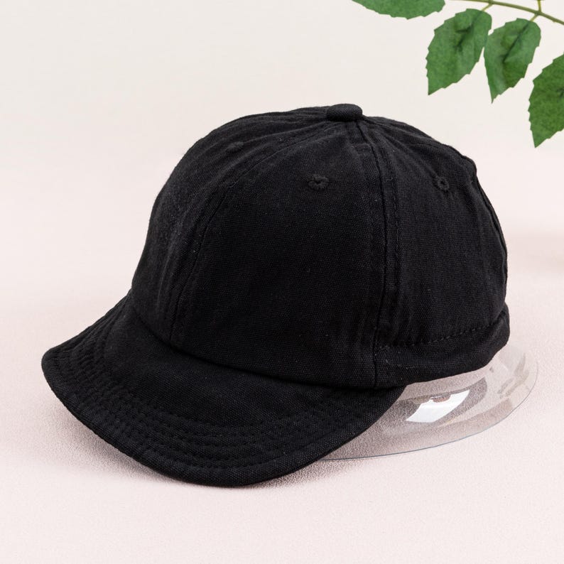 May include: A black baseball cap with a curved brim. The cap is made of a soft, textured fabric.