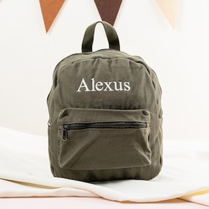 K&ouml;nnte beinhalten: Ein gr&uuml;ner Canvas-Rucksack mit einer Rei&szlig;verschlusstasche vorne und dem Namen "Alexus" in wei&szlig; auf der Vorderseite gestickt.