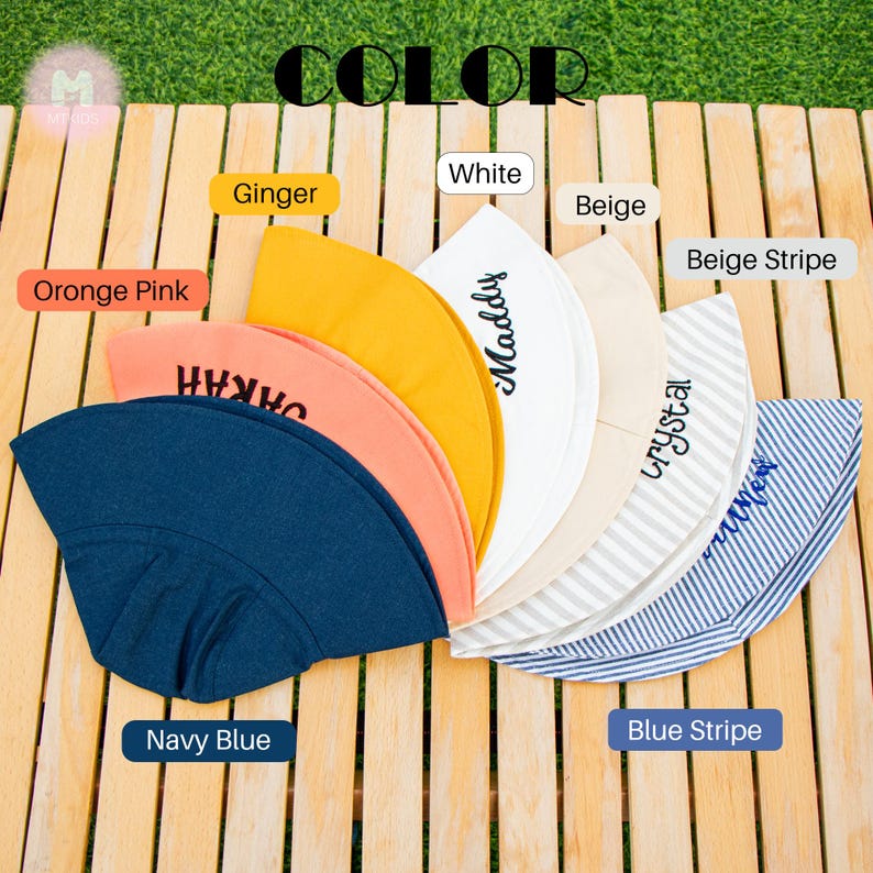 May include: Assortment of 10 sun hats in various colors and patterns, including navy blue, orange pink, white, beige, ginger, beige stripe, and blue stripe. Each hat has a different name embroidered on it.