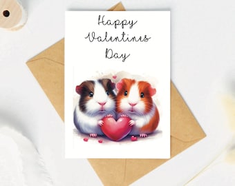 May include: A Valentine's Day card featuring two guinea pigs holding a red heart. The card has the words "Happy Valentines Day" in script. The card is on a white surface with a brown envelope.