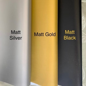 Op de afbeelding: Drie voorbeelden van vinylfolie in verschillende kleuren: Matt Zilver, Matt Goud en Matt Zwart.