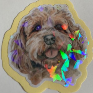 May include: A sticker featuring a brown and white dog with a happy expression. The dog's fur is textured and the sticker has a holographic finish.