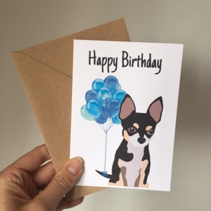May include: A birthday card with a black and white chihuahua dog holding blue balloons. The card says "Happy Birthday".