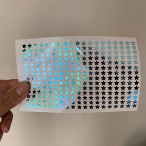 A sheet of iridescent blue star stickers. The stickers are arranged in a grid pattern.