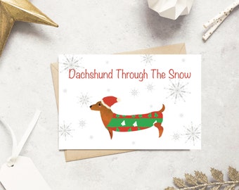 May include: A Christmas card with a cartoon dachshund wearing a Santa hat and a sweater with a Christmas tree pattern. The text on the card reads "Dachshund Through The Snow".
