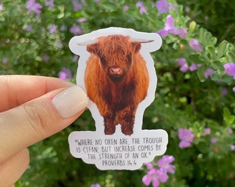 May include: A sticker featuring a brown Highland cow with a quote from Proverbs 14:4, "Where no oxen are, the trough is clean: but increase comes by the strength of an ox."