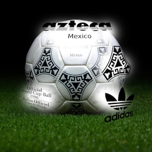 May include: A white and black soccer ball with the word "Azteca" above it. The ball has black geometric patterns and the Adidas logo. Text on the ball reads "Official World Cup Ball 1986".