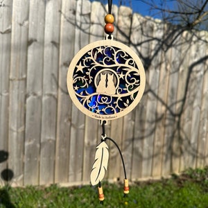May include: A wooden cat-themed suncatcher with a circular design. The suncatcher features two cat silhouettes, stars, and a heart. The text "Made in Indiana" is visible. A feather and beads hang below.